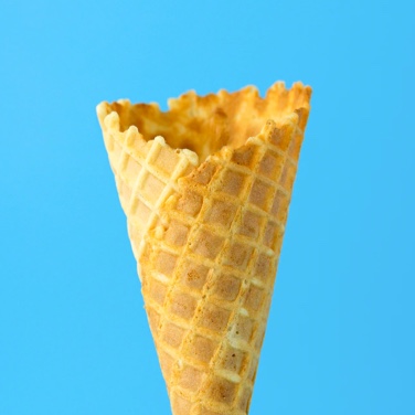 An empty ice-cream waffle cone in front of a sky blue background.