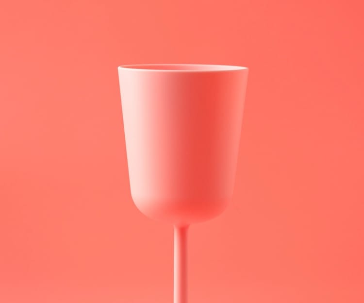 A pink stemmed glass on a pink background