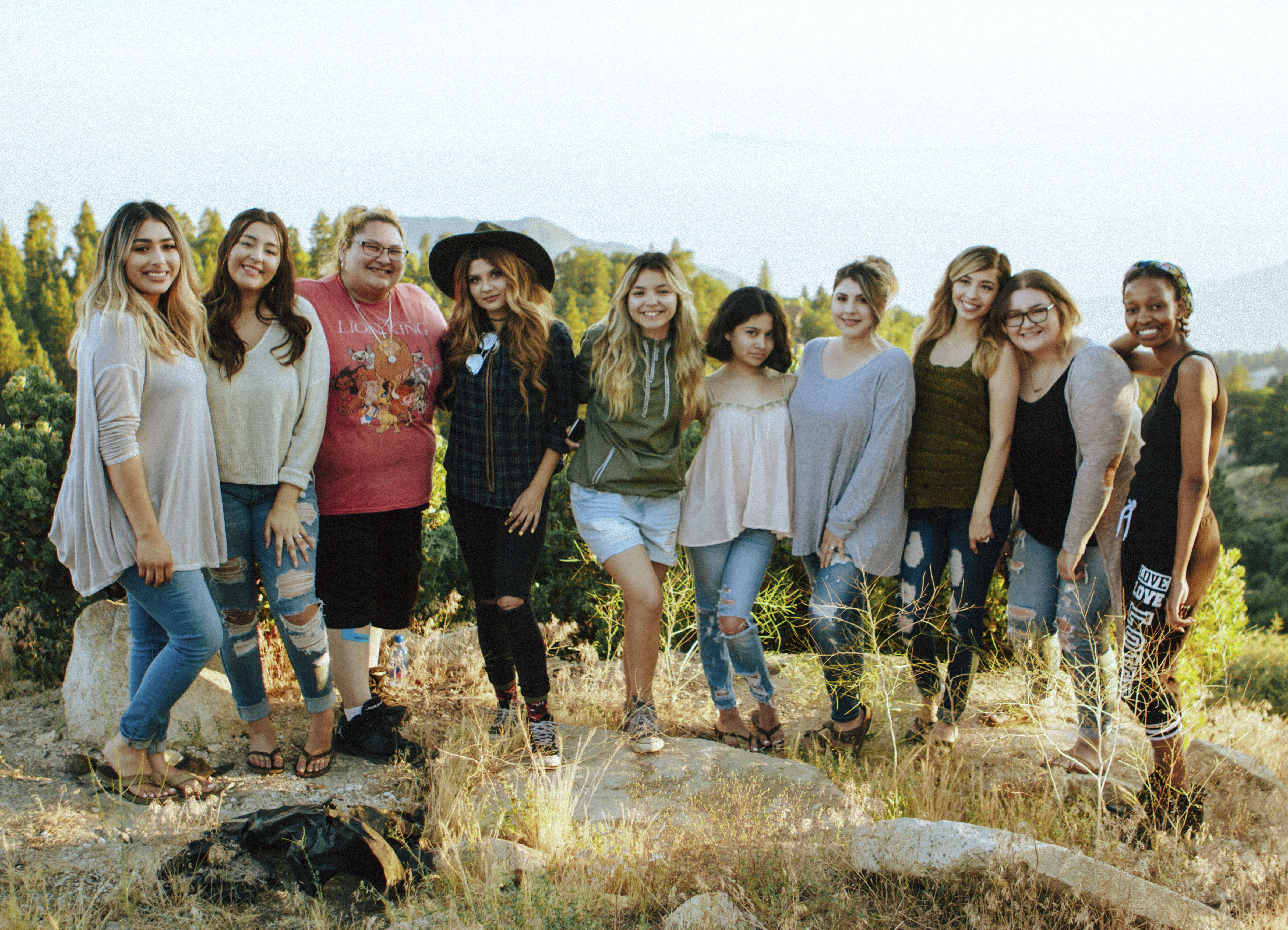 group of 10 people standing together outside in a line with their arms around each other